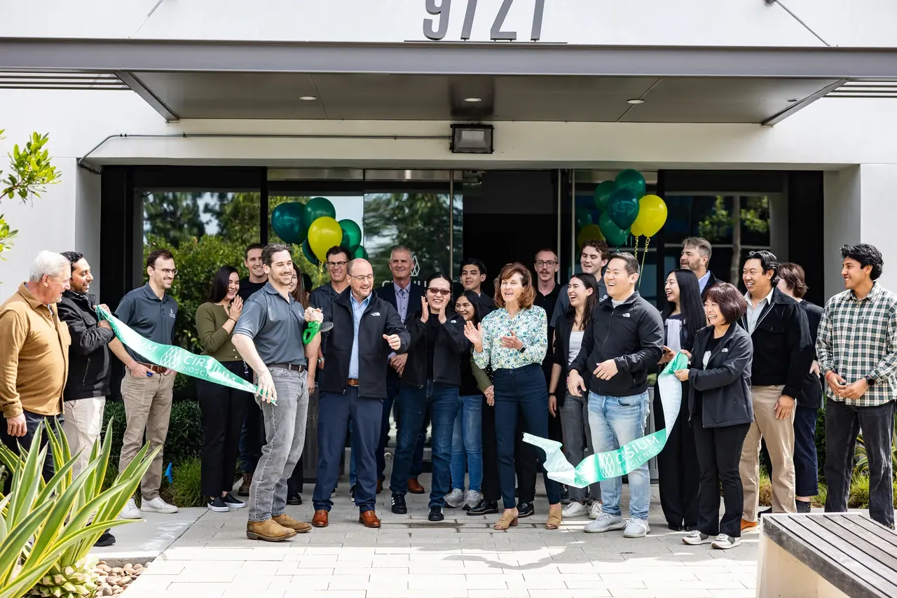 A team celebrating a ribbon-cutting at a new storefront